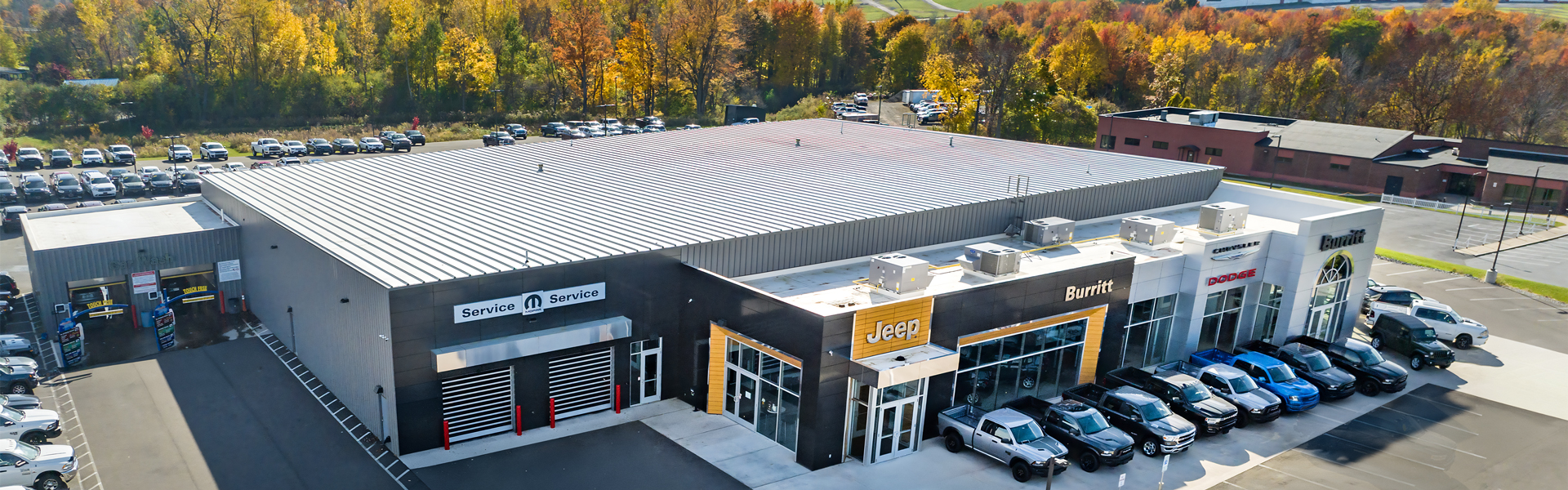 large auto dealership with a metal roof, service bays, and vehicles parked in front